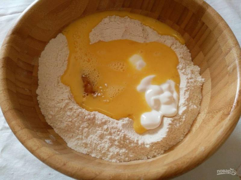 Сформируйте из сухой массы горку с углублением в центре, влейте яйца (слегка взбитые), добавьте сметану и мёд.