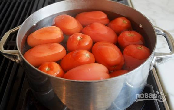 1. Помидоры надрежьте крестом на верхушке. Затем выложите их в кастрюлю, влив воду. Варите томаты в течение пары минут, чтобы начала отходить кожица.