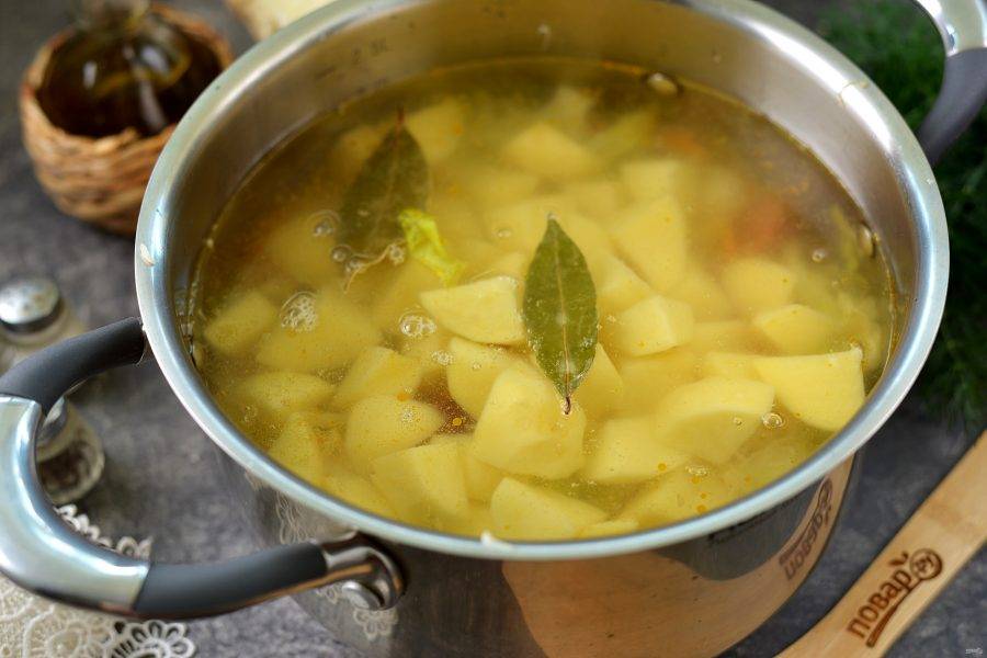 Картофель нарежьте крупным кубиком, добавьте в кастрюлю, влейте воду, выложите лавровый лист. После закипания воды варите суп около 25-30 минут, до полного приготовления картофеля.