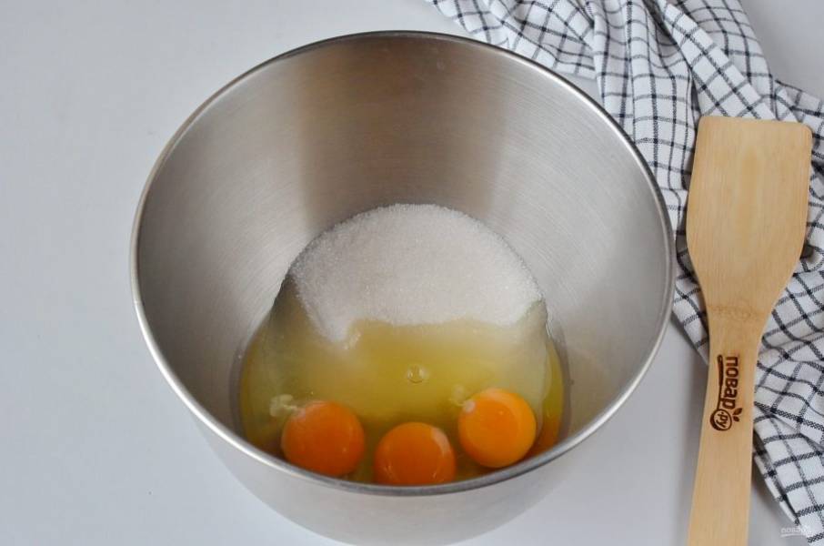 Яйца и один стакан сахара (без 2 ст.л. ложек) выложите в чашу миксера и взбейте на максимальных оборотах 3-4 минуты, пока не образуется плотная пышная масса.