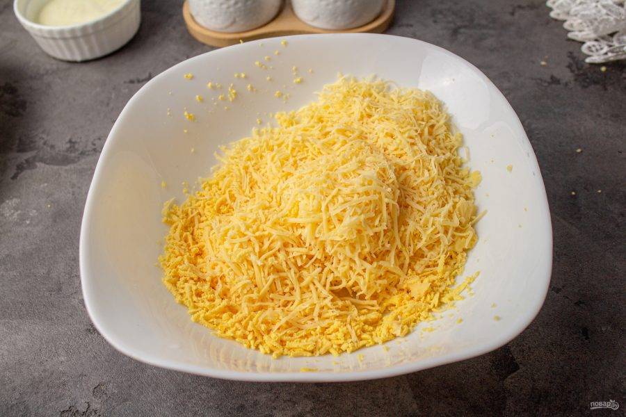 Сыр также натрите на мелкой терке, соедините с желтками.