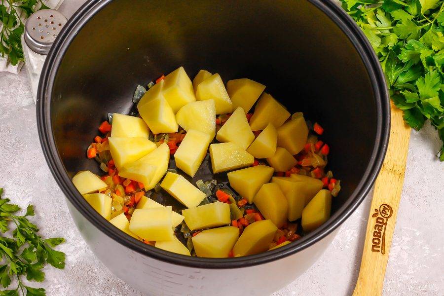 Затем нарежьте средними кубиками промытый картофель и добавьте в чашу. Обжарьте еще 1-2 минуты.