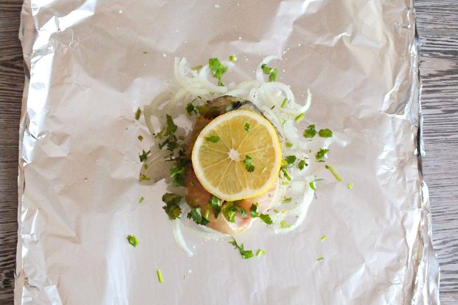 На стейк выложите кружочек лимона, посыпьте нарезанной зеленью.