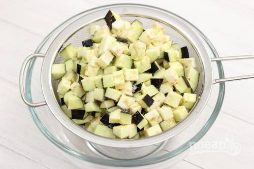 1. Нарежьте баклажаны кубиками, поместите их в дуршлаг, посыпьте немного солью, чтобы лишняя влага из овощей вышла. Оставьте минут на 10.