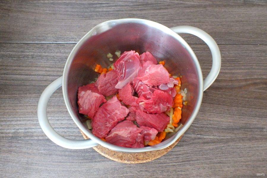 Переложите мясо к обжаренным луку с морковью. Обжаривайте всё вместе в течение 30 минут, помешивая.