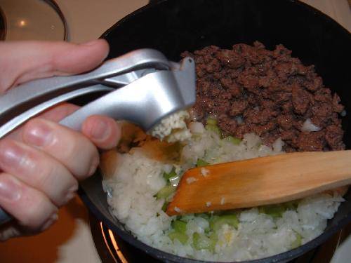 Слегка обжариваем мясо в 2 столовых ложках масла.
Подвиньте мясо к краю сковороды, в свободную половину насыпаем лук, сельдерей и чеснок. Готовим примерно 5-10 минут.