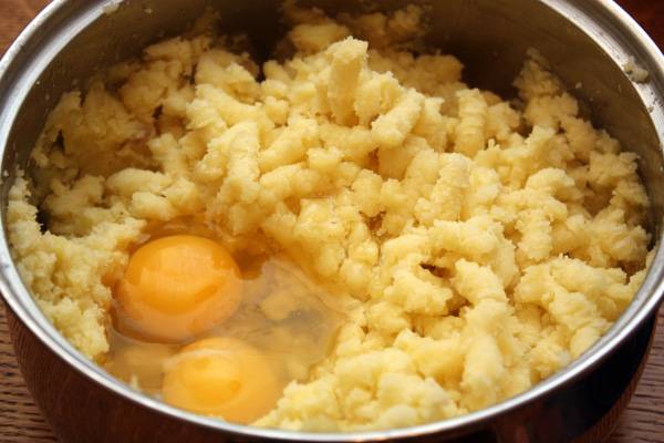 Подождем, пока пюре немного остынет, а затем добавим к нему яйца, муку, соль и молотый перец, тщательно перемешаем все ингредиенты. 