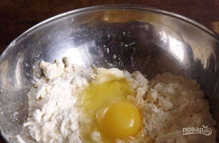 В миску просейте муку, добавьте сахар, натертое на терке холодное сливочное масло. Перетрите все руками в крошку, затем вбейте сырое куриное яйцо. 