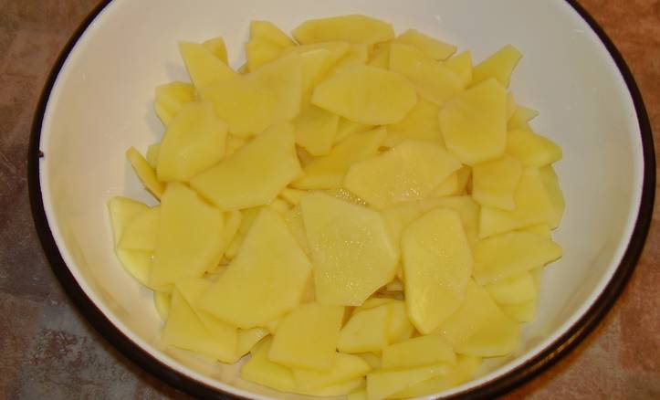 Картофель промойте и очистите, затем нарежьте тонкими пластинками.