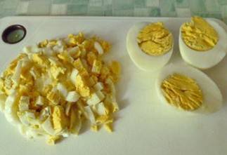 Яйца порежьте на кусочки, часть яиц оставьте на украшение.