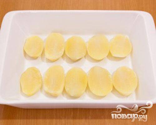 4.	Чистим картофель и каждый разрезаем вдоль на две части. Форму для запекания смазываем маслом и выкладываем на нее картофель. 