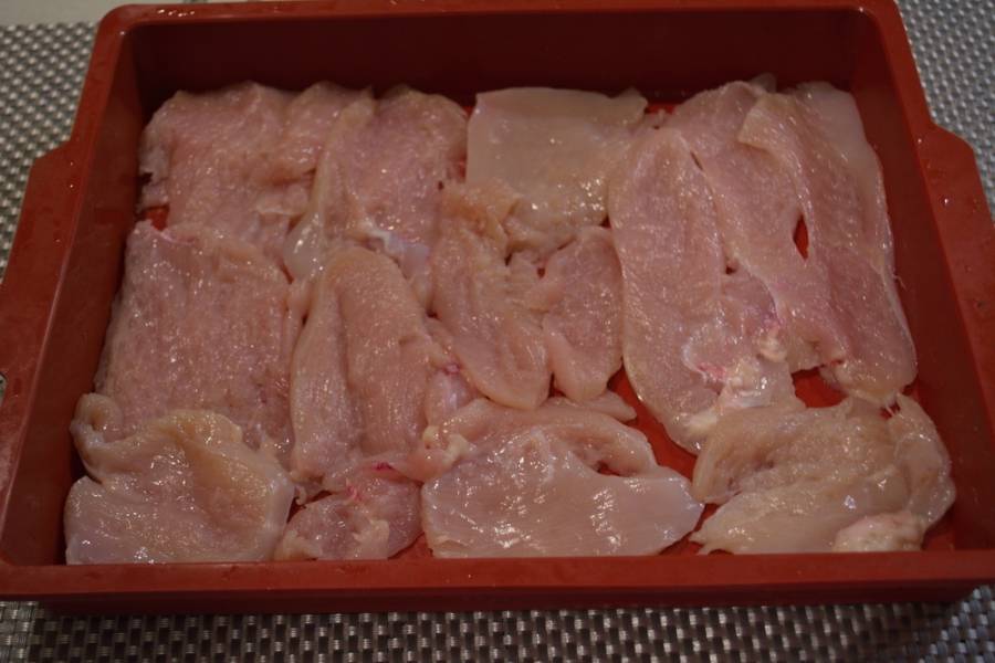 1. Куриное филе нарезать на полоски. Каждую отбить молоточком. Уложить кусочки филе в смазанную маслом форму для запекания. Мясо посолить и поперчить по вкусу.