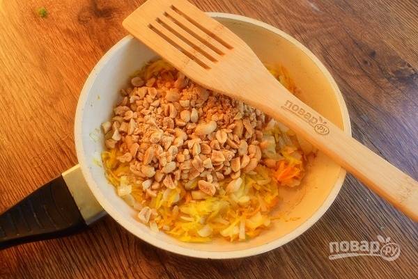 На отдельной сковороде разогрейте 1-2 ст. л. масла, обжарьте измельченный лук и тертую морковь до золотистой корочки. Добавьте жареный арахис, перемешайте и прогрейте 1 минуту.