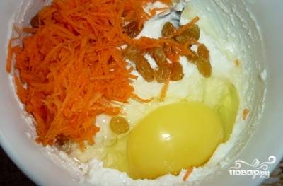 Изюм залейте кипятком на 15 минут. Необходимое количество моркови натрите на тёрке. Смешайте в миске все ингредиенты: изюм, манку, яйцо, творог, морковь, сахар.