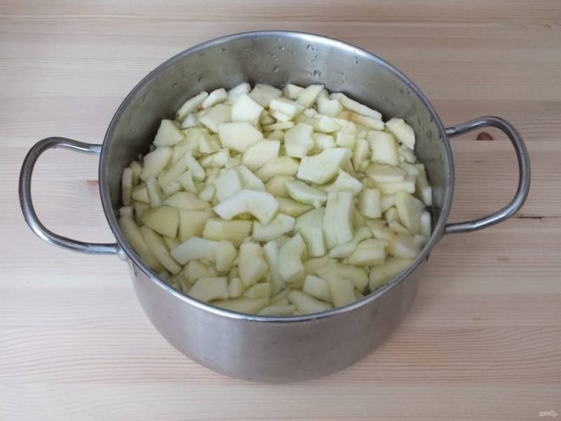 Нарежьте очищенные яблоки на четвертинки. Чтобы плоды не потемнели, в кастрюлю налейте воду и добавьте соль (соотношение на 1 литр воды 10 грамм соли). В этом растворе яблоки хорошо сохраняют цвет. 