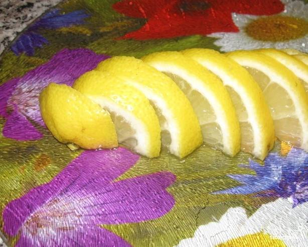 Лимон вымойте и нарежьте на небольшие дольки. Если будут попадаться косточки, то их следует достать. Положите лимон в кастрюльку с сухофруктами и уменьшите огонь до минимума. 