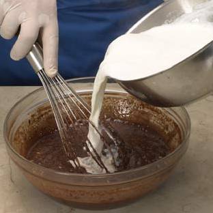 Смешайте порошок какао, затем добавьте толченые булочки (по Итальянскому рецепту это Amaretti) и ром. Нагрейте молоко отдельно и затем добавьте его к смеси, непрерывно помешивайте венчиком.