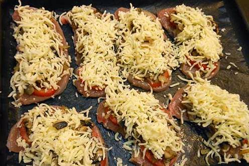Смажьте противень растительным маслом, выложите на него индейку. Поверх мяса выложите нарезанные пластинками помидоры, затем — грибы и, наконец, тертый сыр.