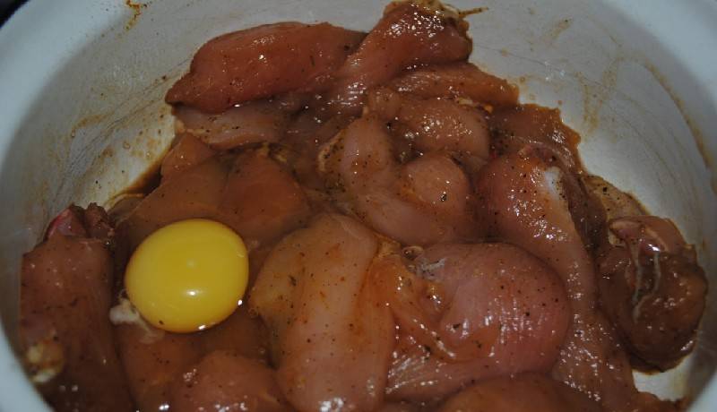 Курицу разморозим, промоем и очистим от пленок. Добавим яйцо и соевый соус, а также — специи. Пусть курочка в этой смеси постоит хотя бы полчаса. 