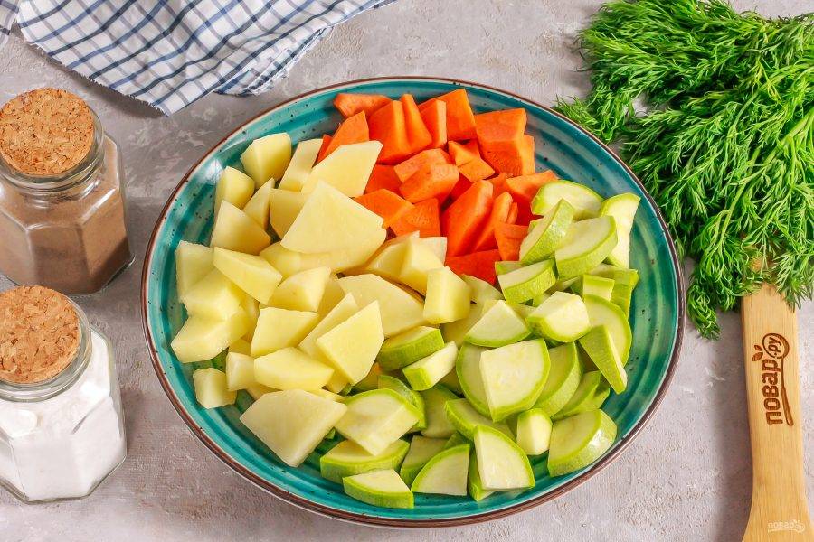 Тем временем очистите картофель и морковь от кожуры, с кабачка срежьте хвостики. Промойте овощи и нарежьте средними кубиками.