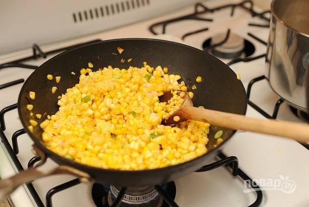 4. Срежьте с початков зерна кукурузы. На отдельной сковороде разогрейте немного масла. Выложите туда немного лука (белая часть от перьев зеленого лука) и обжарьте буквально минутку. После добавьте зерна кукурузы и на среднем огне, помешивая, томите минут 5-7. 