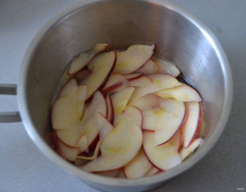 Возьмите сотейник, всыпьте 1 столовую ложку сахара (от общего количества по рецепту), доведите до кипения, выложите нарезанные дольки яблок, кипятите 2 минуты, дайте им полежать в горячем сахарном сиропе пока занимаетесь тестом.