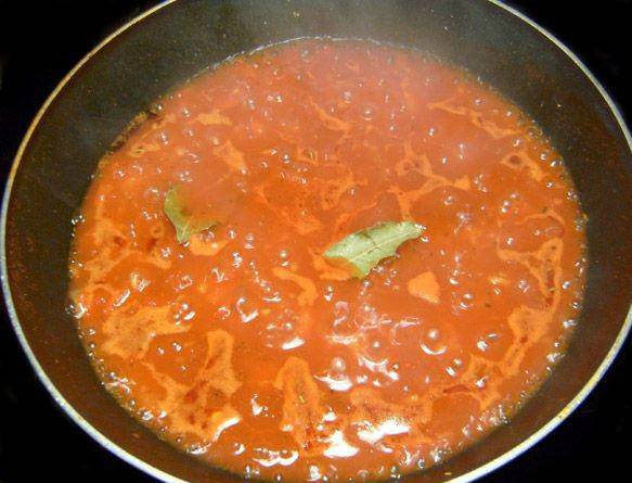 Режем мелко помидоры и чеснок. Обжариваем на отдельной сковородке 10 минут. Добавляем томатную пасту, лавровый лист, немного воды и сахар. Когда смесь закипит, лавровый лист убираем.