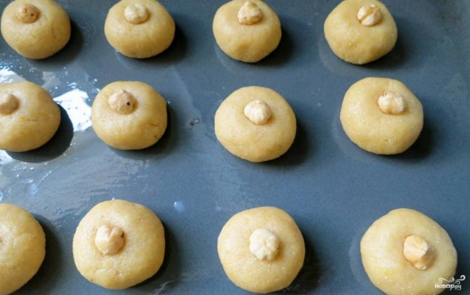 2. Лепим печенье, отламывая шарики теста и слегка приплющивая их. Украшаем каждое небольшим кусочком орешка или ягодкой. Выпекаем на противне с растительным маслом примерно 25 минут при 180 градусах. 