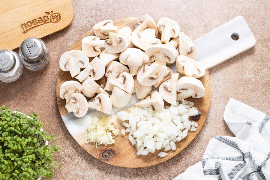 Шампиньоны помойте, разрежьте на 2-4 части. Если грибы крупные, можно нарезать их кубиками или пластинами. Репчатый лук нарежьте кубиками, а чеснок очистите и пропустите через пресс.