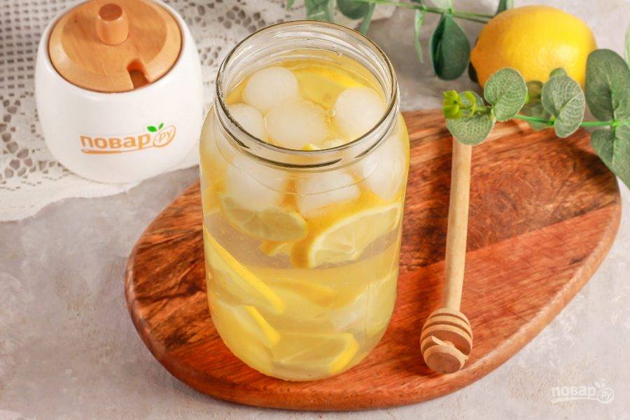 Влейте охлажденную или ледяную воду и тщательно все перемешайте. Оставьте на 5 минут, снова перемешайте, чтобы размешался мед. По желанию можно измельчить лимон на мясорубке или погружным блендером, если вы не против кусочков фруктов в напитке.