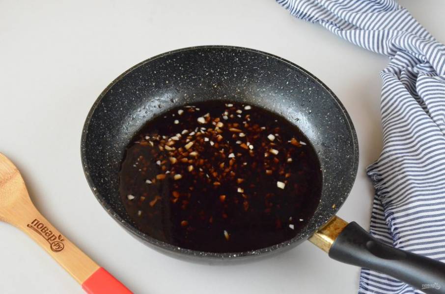 В сковороду влейте соевый соус, рисовый уксус, добавьте мелко рубленый чеснок, доведите до кипения.