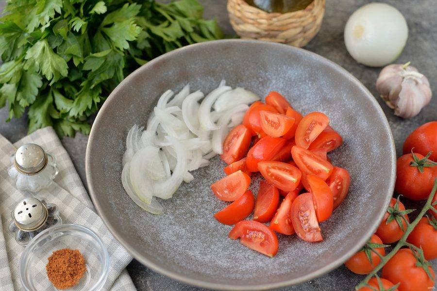 Нарежьте лук полукольцами, помидоры черри — четвертинками, выложите овощи в глубокую удобную миску.
