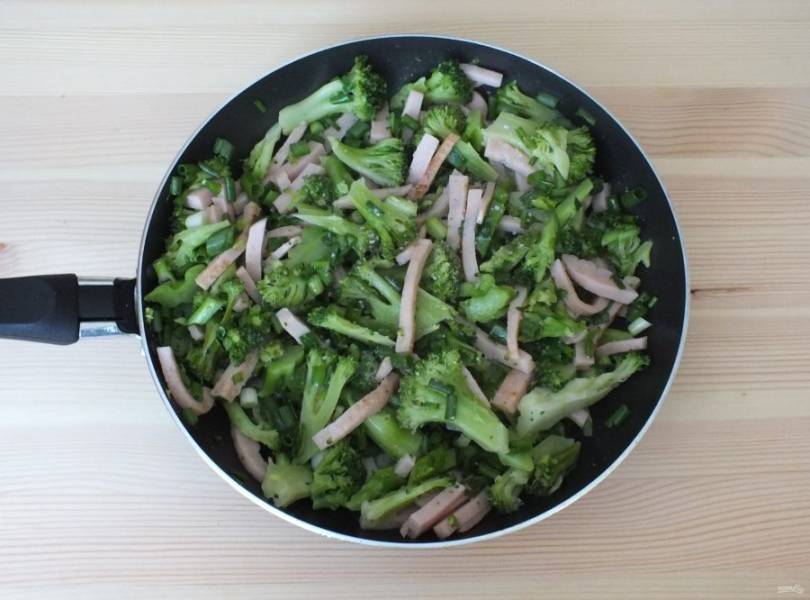 Добавьте к ветчине брокколи, зеленый лук, соль, перец и обжарьте на малом огне в течение 15 минут.
