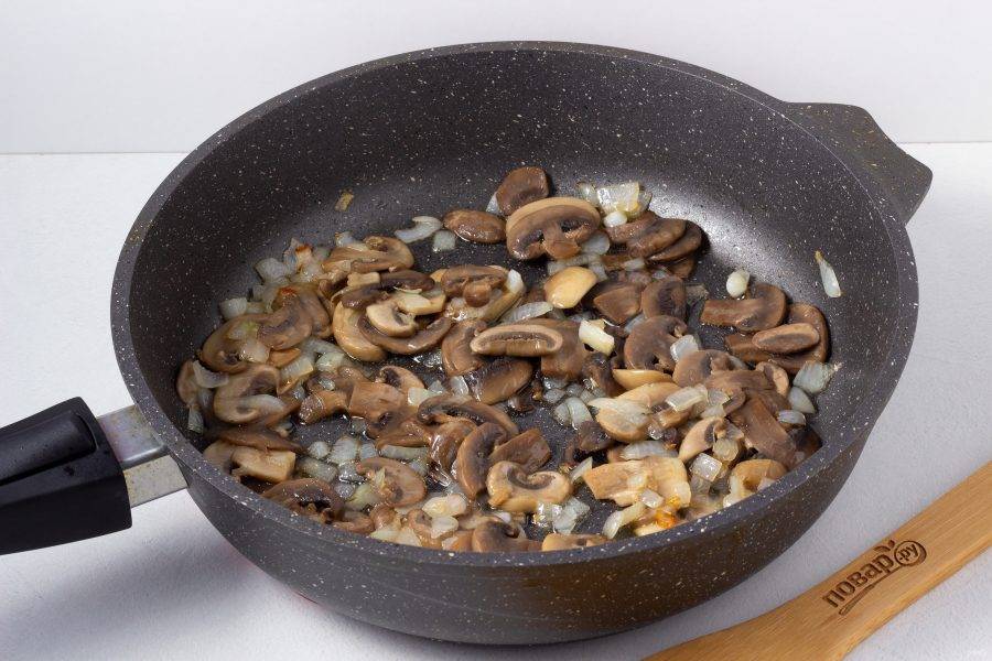 В сковороде на оливковом масле обжарьте мелко нарезанный лук, затем добавьте нарезанные пластинами грибы. Обжаривайте 4-5 минут.