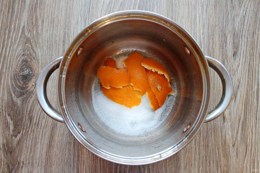 В кастрюлю выложите цедру апельсина и всыпьте сахар.