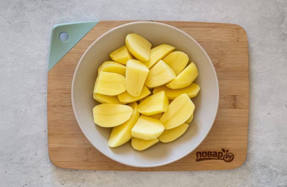 Картофель помойте, очистите от кожуры и нарежьте крупными дольками. Небольшие клубни можно просто разрезать пополам. Посыпьте черным молотым перцем и перемешайте.
