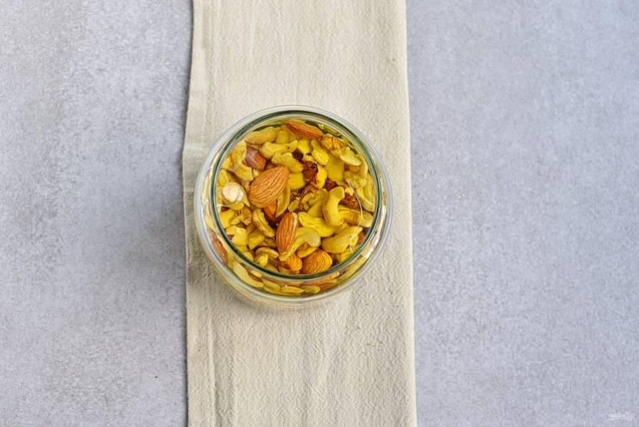 Залейте орехи медом в два-три приема, перемешивая смесь ложкой, чтобы каждый орех был покрыт медовой «мантией».