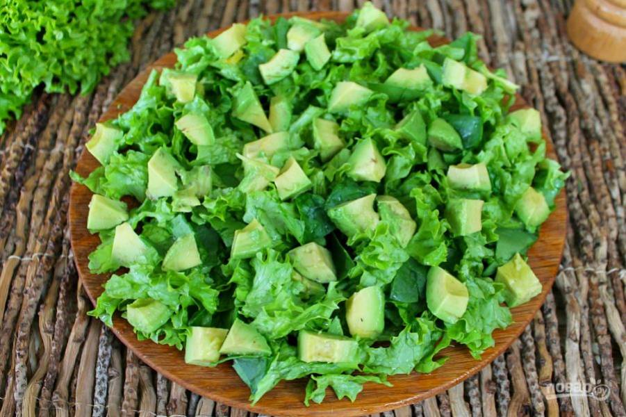 Авокадо чистим, разрезаем на кусочки и выкладываем на листья салата.