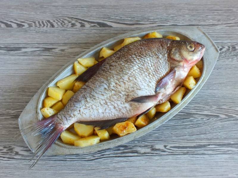 Из брюшка рыбы извлеките лимон. Переложите рыбу на картофель.