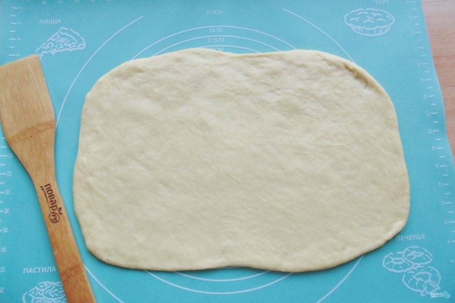 Достаньте тесто из миски, обомните и раскатайте в прямоугольный пласт толщиной 4-5 мм.