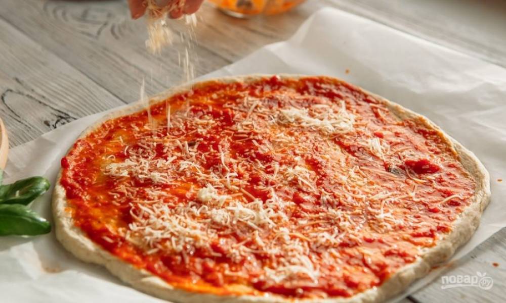 Готовое тесто разделите на 2-3 части. Из каждой раскатайте форму для пиццы. Смажьте её томатным соусом и маслом. Сверху натрите пармезан.