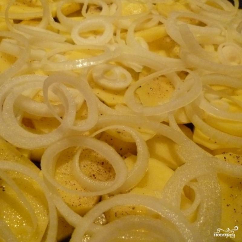 Лук чистим, нарезаем тонкими кольцами и равномерно укладываем поверх картофеля. Солим, перчим.