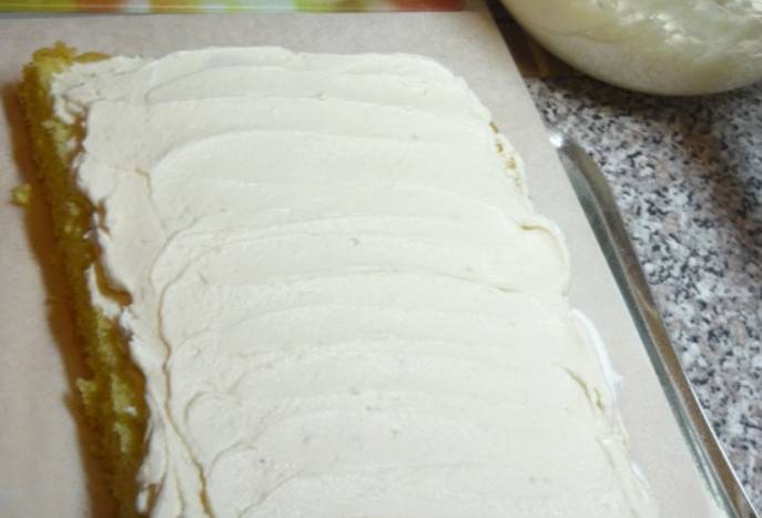 Разрезаем бисквит на три коржа, каждый пропитываем сахарным сиропом. Смазываем коржи кремом и выкладываем друг на друга. Формируем квадратный торт, верхушку и бока торта также покрываем кремом.