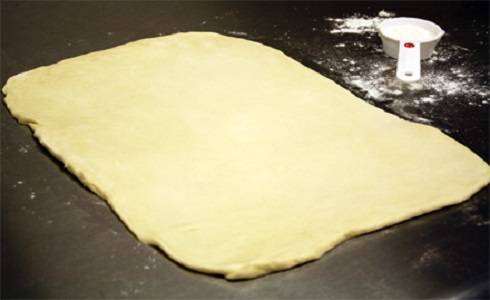 2. Когда тесто подошло, его нужно еще раз вымесить и раскатать на присыпанной мукой поверхности. Из теста сформировать прямоугольник. 