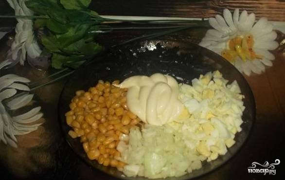 3. Возьмите салатницу, выложите в нее морскую капусту. Положите яйца, лук. Откройте баночку с кукурузой, слейте из нее жидкость. Затем переложите кукурузу в салатницу. Заправьте майонезом.