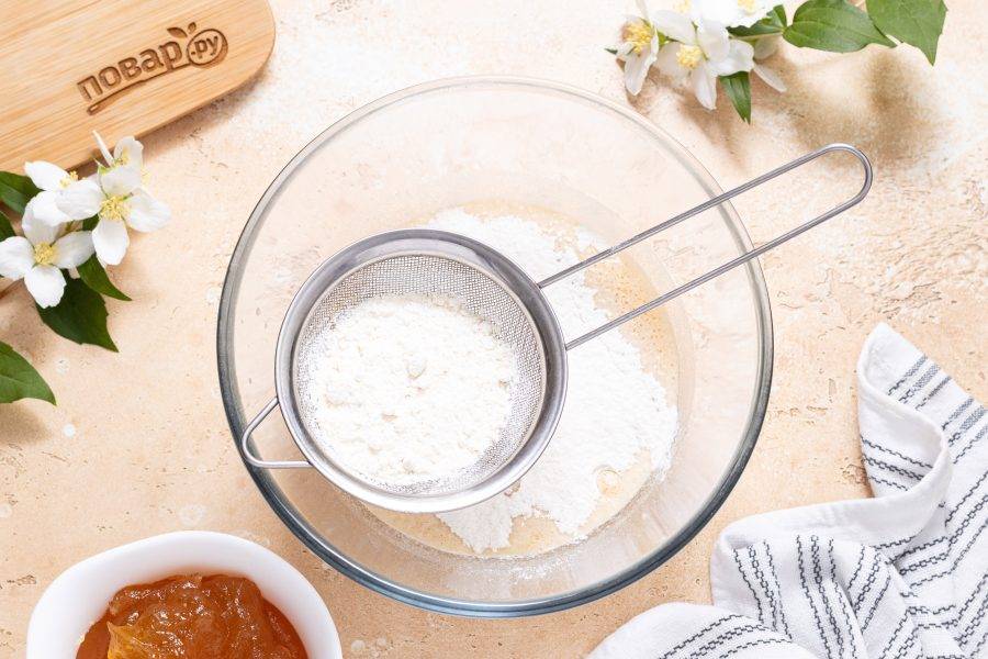 Начните просеивать частями муку в миску.