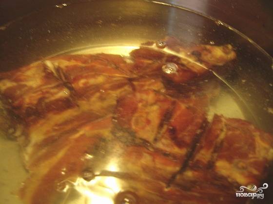3. Далее выкладываем обжаренные ребрышки в глубокую кастрюлю, заливаем водой. Солим и перчим, добавляем розмарин. Тушим на слабом огне в течение 1 часа, пока мясо не станет отделяться от костей. Подливаем воду по мере её испарения.