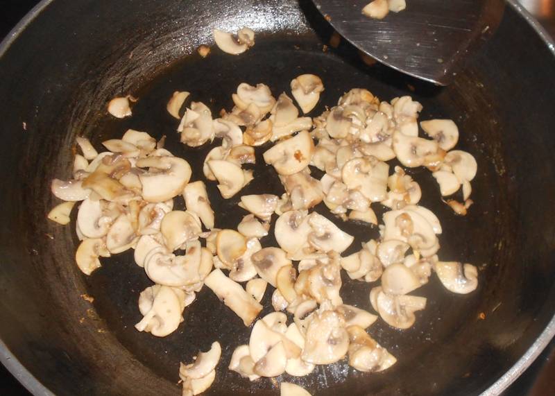 Ставим на огонь сковороду, наливаем в нее немного растительного масла и разогреваем его. В масло выкладываем нарезанные пластинками грибы, обжариваем их до золотистого цвета и перекладываем на тарелку. 
