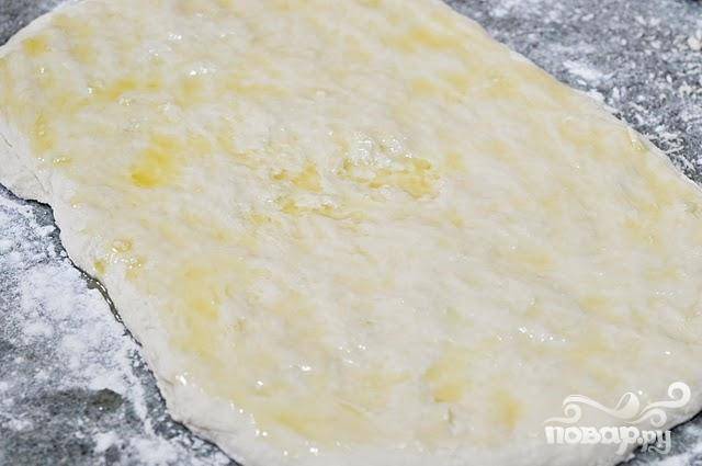 4. Вылить 2 столовые ложки топленого масла на тесто и равномерно смазать его пальцами. 
