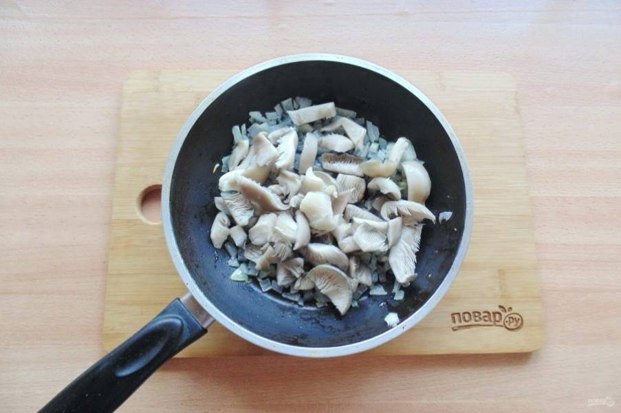 У вешенок обрежьте утолщение возле корня, помойте и нарежьте грибы. Добавьте в сковороду с луком. Жарьте вешенки с луком 7-9 минут до испарения жидкости.